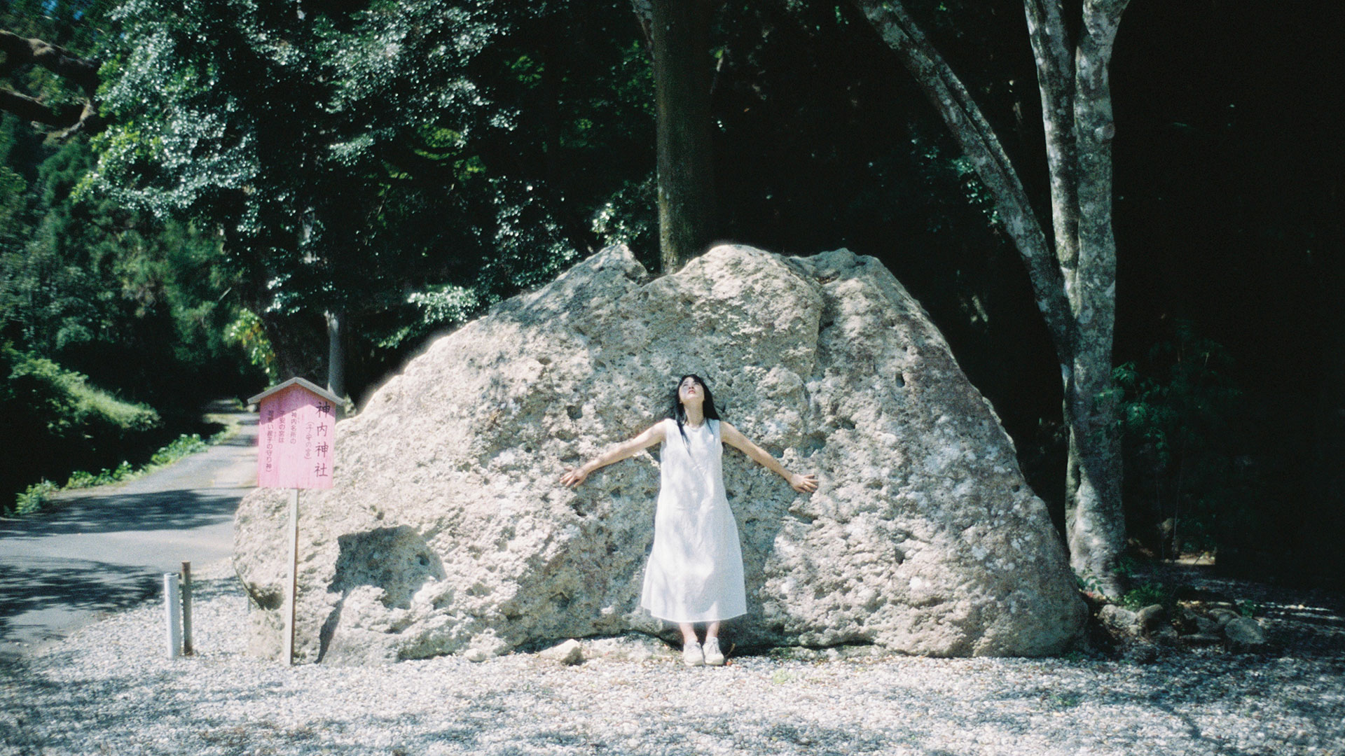 神内神社境内入口の巨石と、Kodak PORTRA 400の柔らかな光に包まれて立つ女性の姿