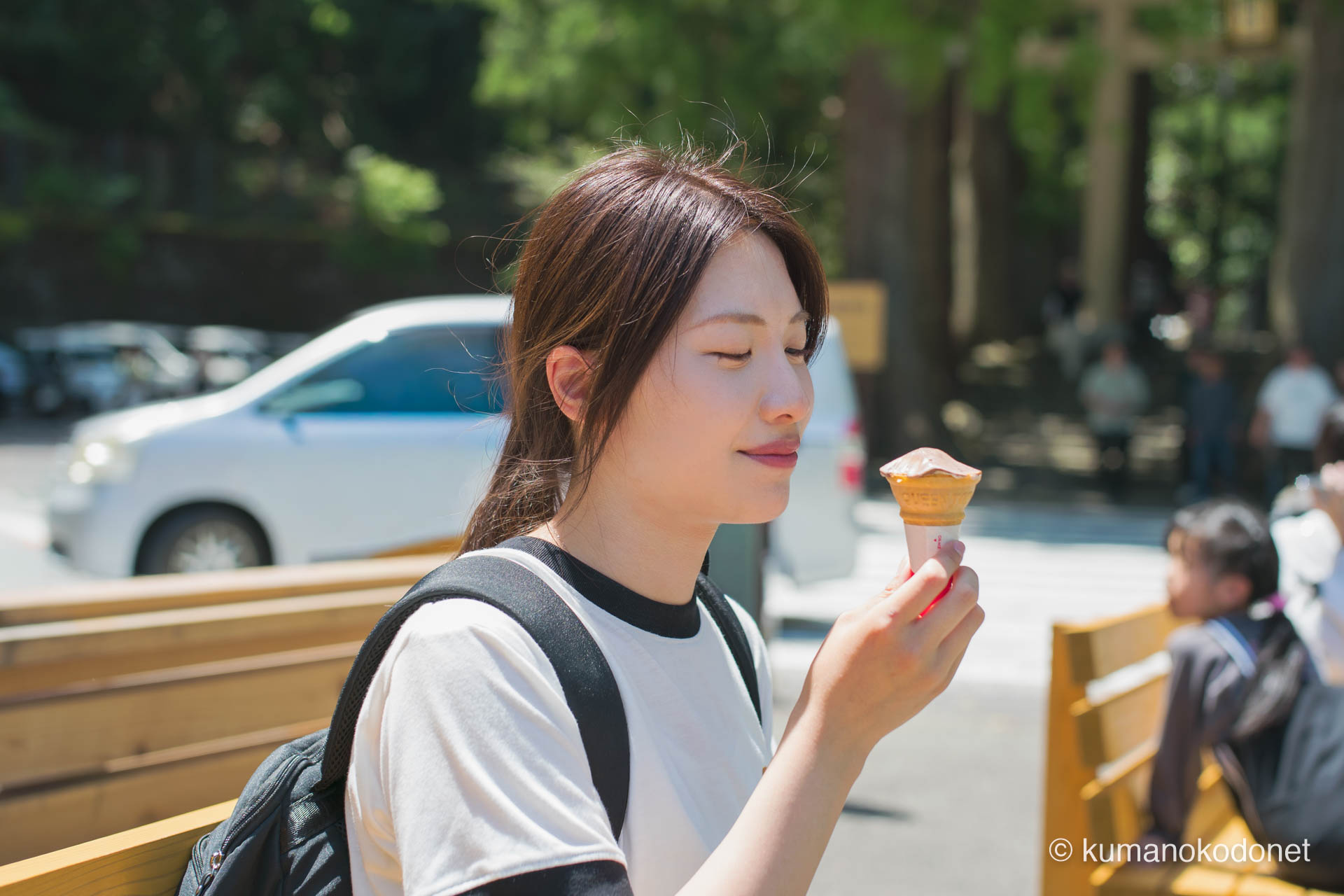 参道のベンチでソフトクリームを味わう女性