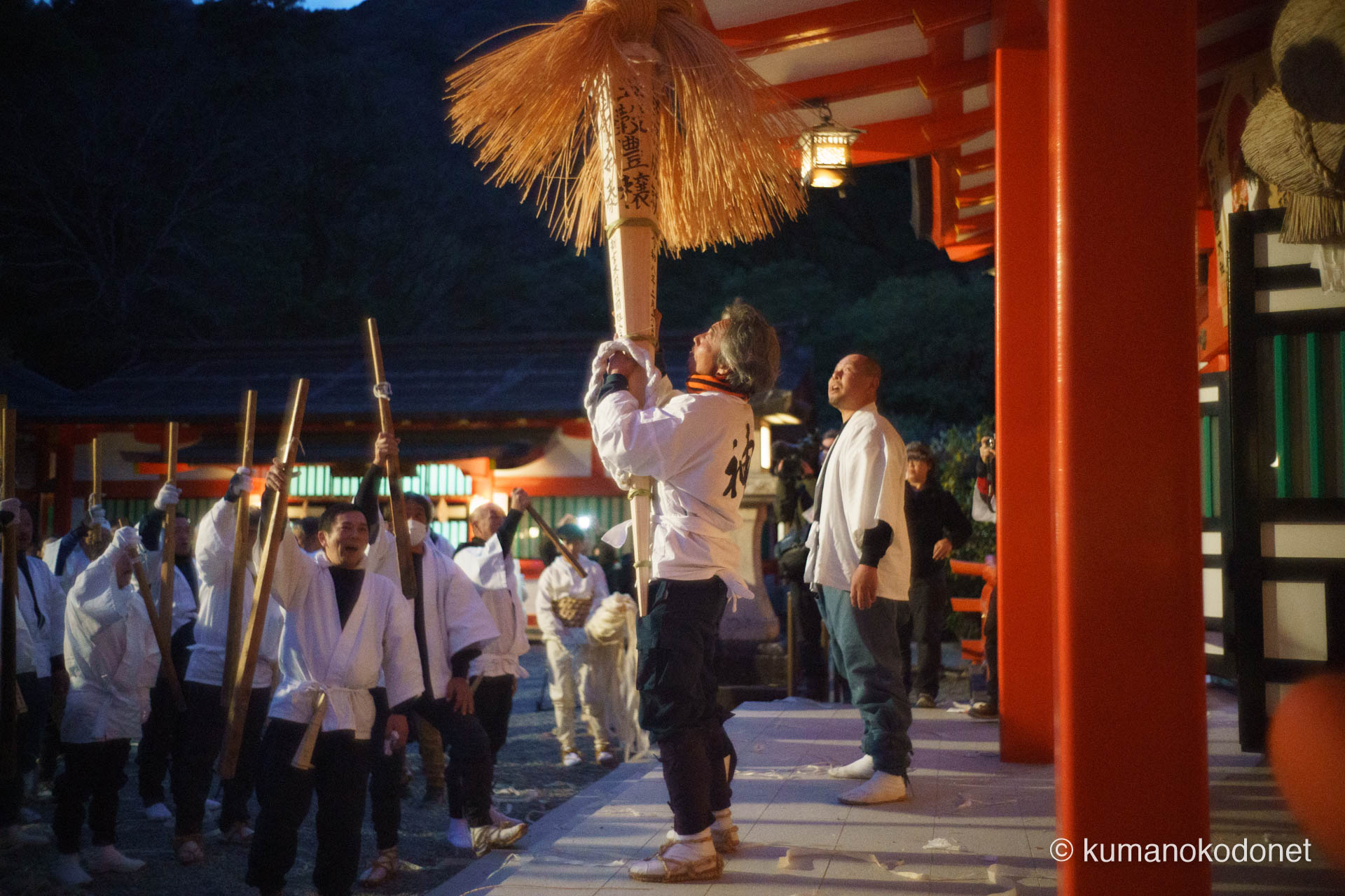 熊野速玉大社の拝殿前で、天高く大松明を掲げる介釈と、呼応するように雄叫びを上げる神職と介釈たちの姿。静寂を破る言霊が夜の境内に響き渡り、人知を超えたエネルギーが炎へと変わる直前の、原始的な生命力に満ち溢れた光景。 ｜ Kumano Hayatama Taisha, Shingu, Wakayama ｜ SONY α7 ｜ 2026