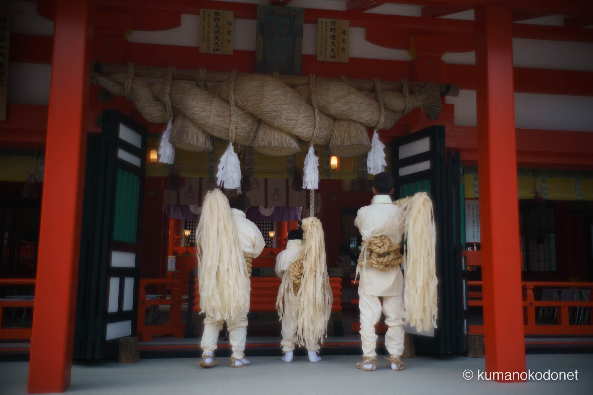 熊野速玉大社の拝殿前、大きな注連縄の下で祈りを捧げる上り子たちの記録。中央で伝統の装束に身を包む幼い「初上り」の少年と、その両脇を支えるように立つ大人の上り子の後ろ姿。世代を超えて守り継がれる信仰と多幸感に満ちた瞬間の記録。 ｜ Kumano Hayatama Taisha, Shingu, Wakayama ｜ SONY α7 ｜ 2026