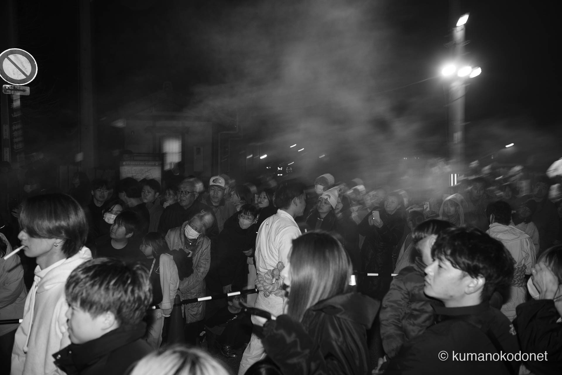 神倉山の麓、上り子たちが駆け抜けた後の街を包み込む、観衆の吐息と松明の煙が混ざり合った白濁した熱気。光に照らされた煙が幻想的な層を成し、待ちわびる人々の期待と興奮が物理的な温度となって空間を支配する、新宮の夜の圧倒的な群像。 ｜ Kamikura, Shingu, Wakayama ｜ SONY α7 ｜ 2026