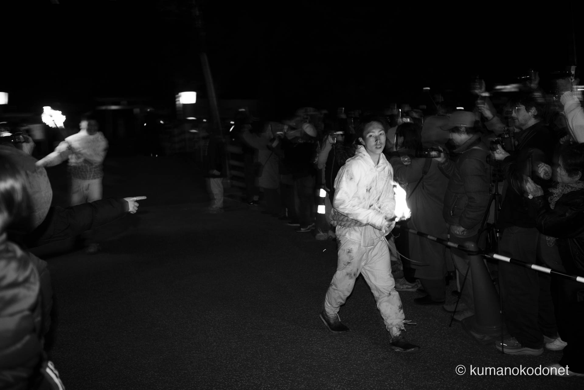 神倉山の石段を駆け下り、先頭に続いて街へと姿を現した二番手、三番手の上り子たち。沿道の熱い視線を浴びながら、一歩一歩確実に神聖な火を運ぶ男たちの真剣な表情と、夜の闇を次々と塗り替えていく松明の動的な光影を捉えた、神事の躍動。 ｜ Kamikura, Shingu, Wakayama ｜ SONY α7 ｜ 2026