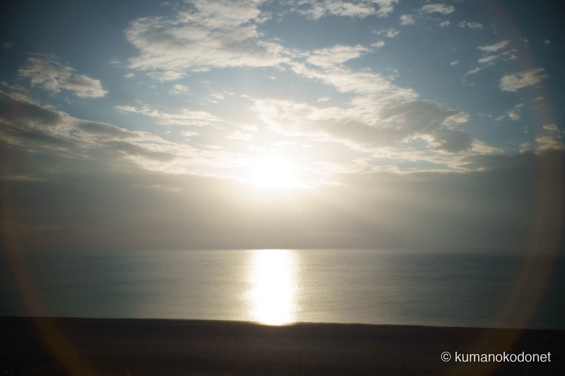 すっかり高く昇った太陽が、王子ヶ浜の海面に強烈な光の道を創り出し、レンズフレアの円環が画面を包み込む。2026年、神事が無事終了したことを祝福するような、神々しい光の記録。 ｜ Oujigahama, Shingu, Wakayama ｜ SONY α7 ｜ 2026