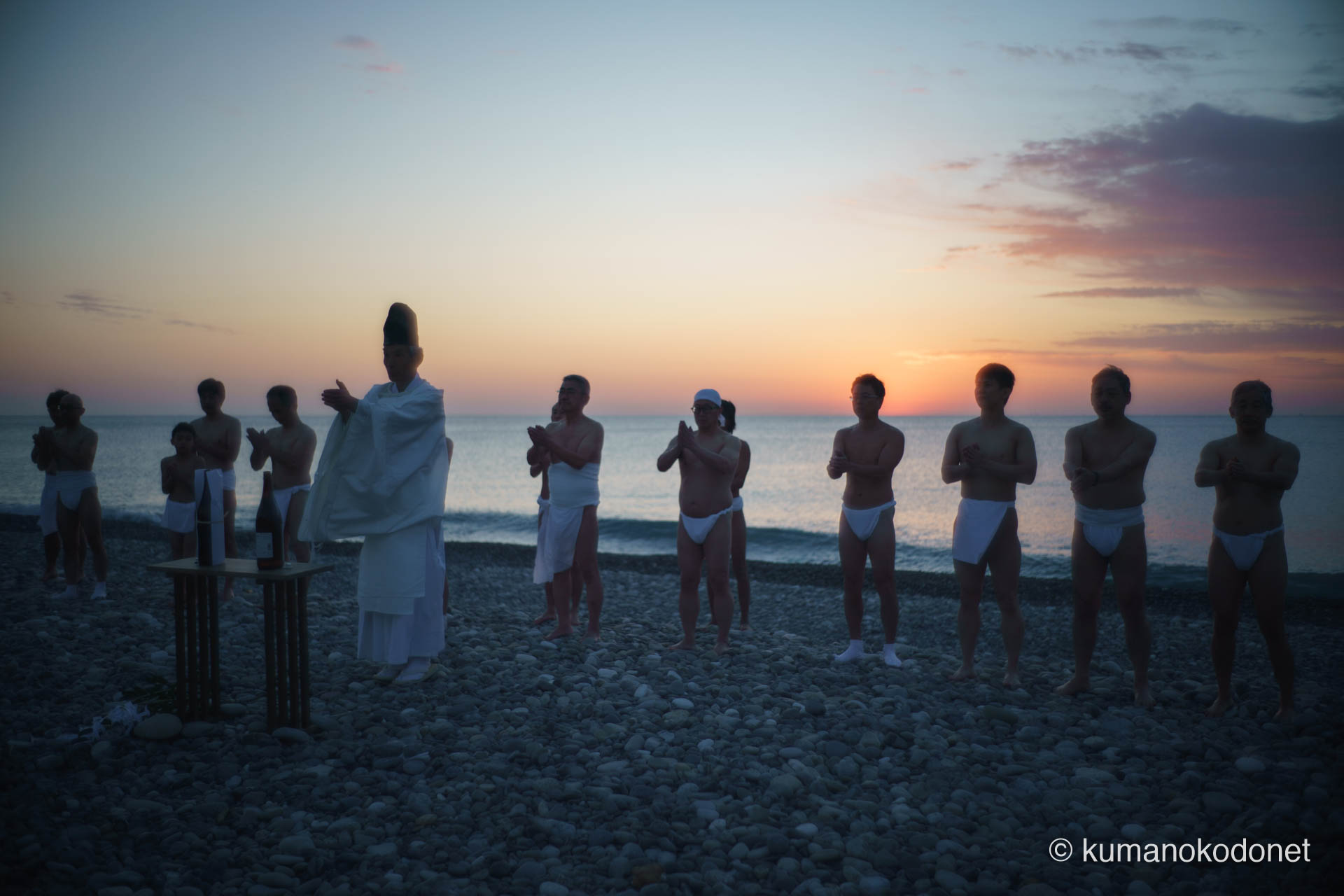 水平線から昇る朝日を背に、神倉神社へ遙拝の合掌を捧げる上り子の一団。2026年、新宮の伝統が始まる瞬間。 ｜ Oujigahama, Shingu, Wakayama ｜ SONY α7 ｜ 2026