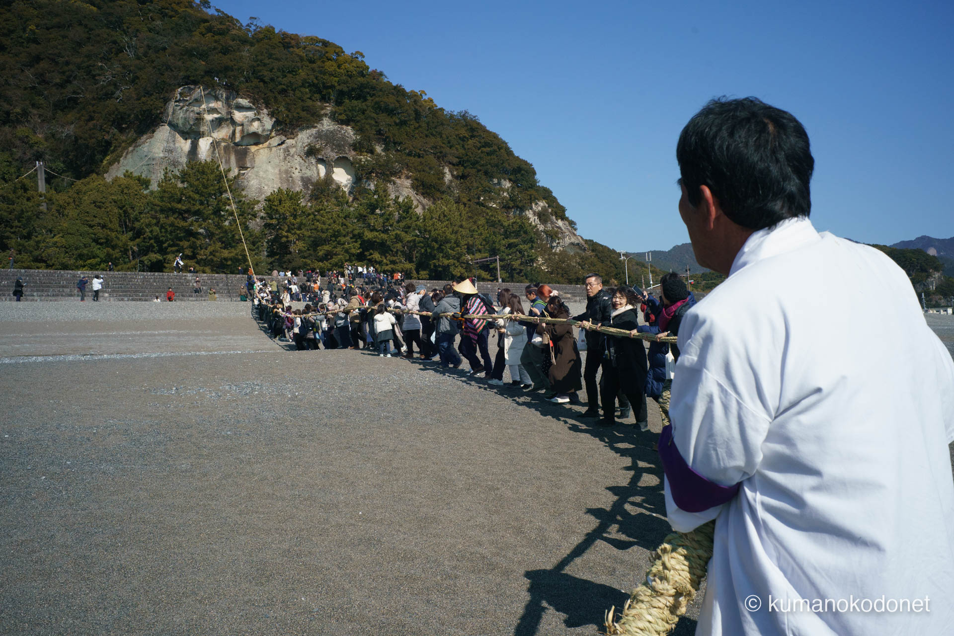 花の窟神社 お綱掛け神事 ｜ 三重県熊野市 ｜ 氏子の背後から花の窟へ向かって伸びる大綱の列 ｜ 2026 ｜ KVA