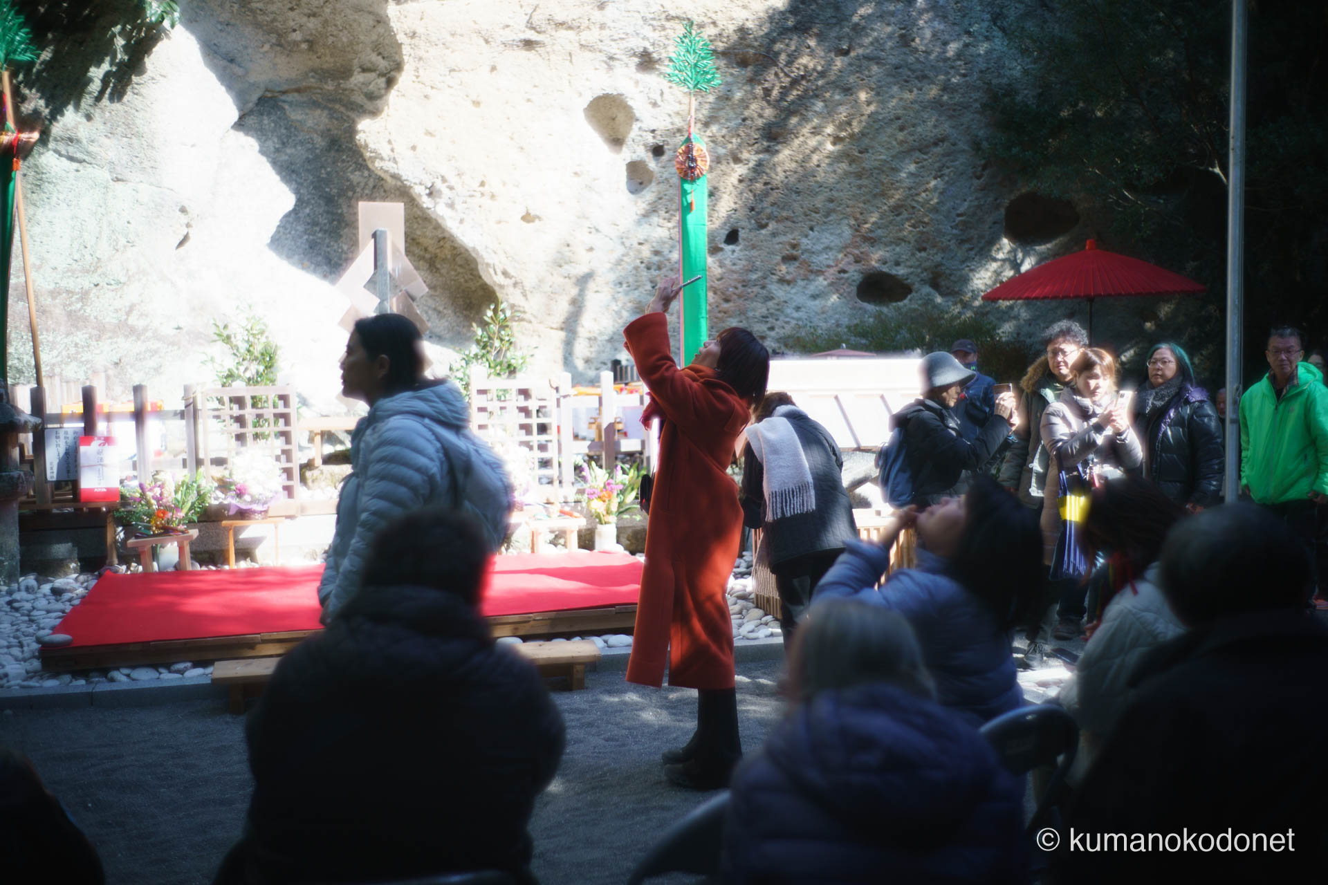 花の窟神社 お綱掛け神事 ｜ 三重県熊野市 ｜ 掲げられた三流の幡をスマートフォンで撮影する参拝客 ｜ 2026 ｜ KVA
