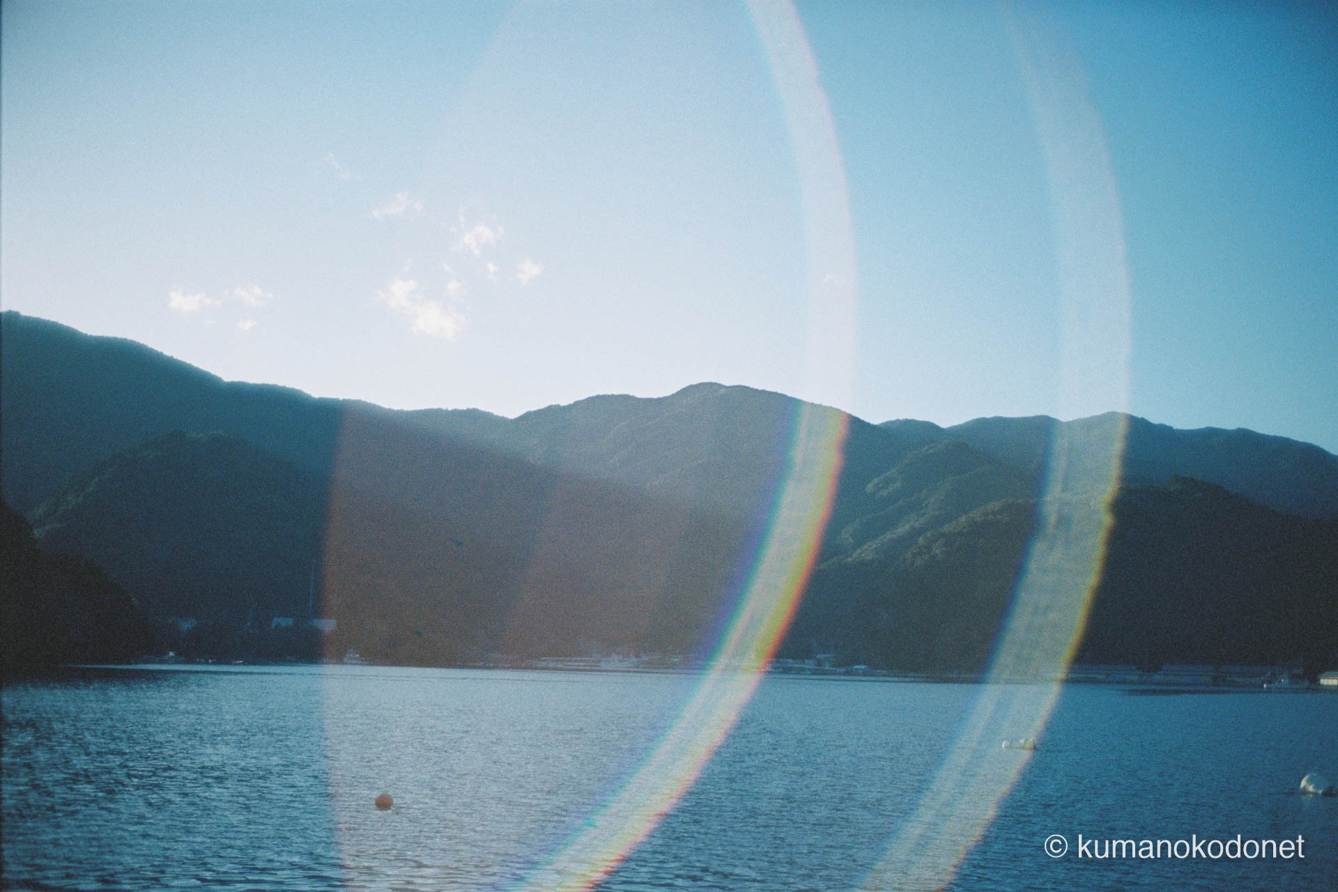 九鬼の海を包み込む、フィルム特有の巨大な虹色のゴースト。逆光の中で輝く水面と、静かに佇む対岸の山々を記憶する。｜ Kuki, Owase, Mie ｜ Kodak Portra 400 ｜ 2026
