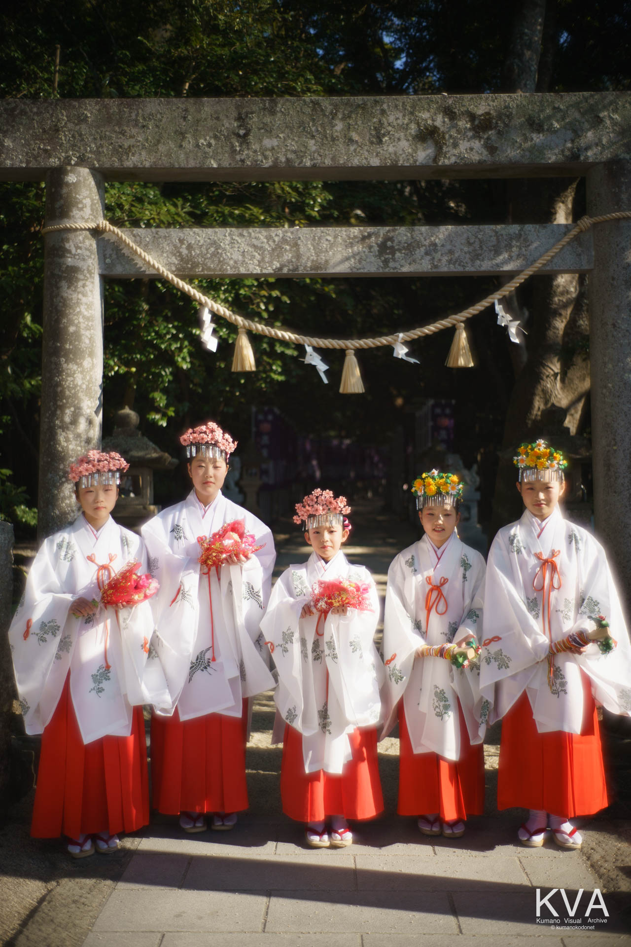 鳥居の前に整列した巫女たちの集合写真