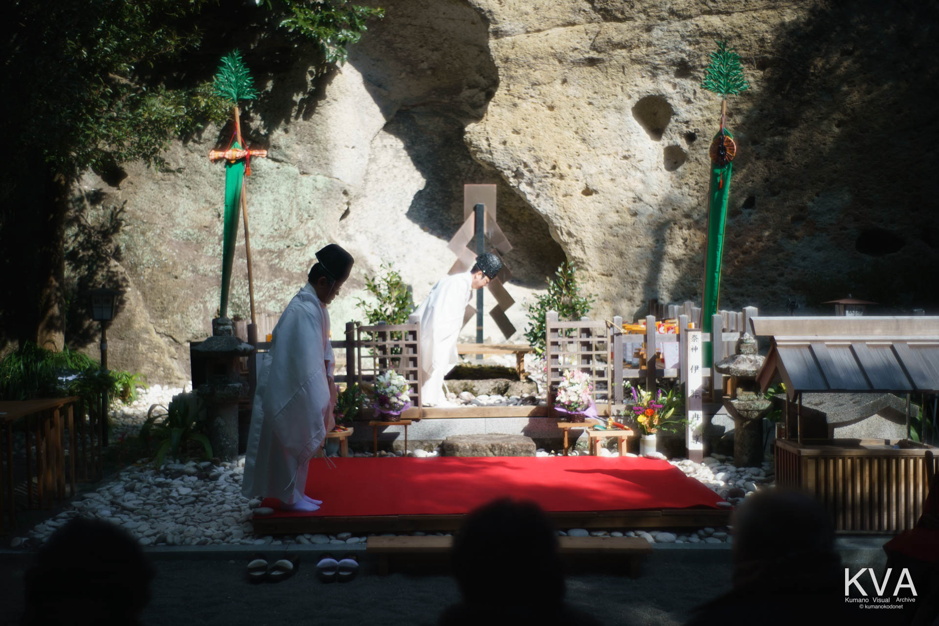 岩窟を背に神前で拝礼を行う神職たち