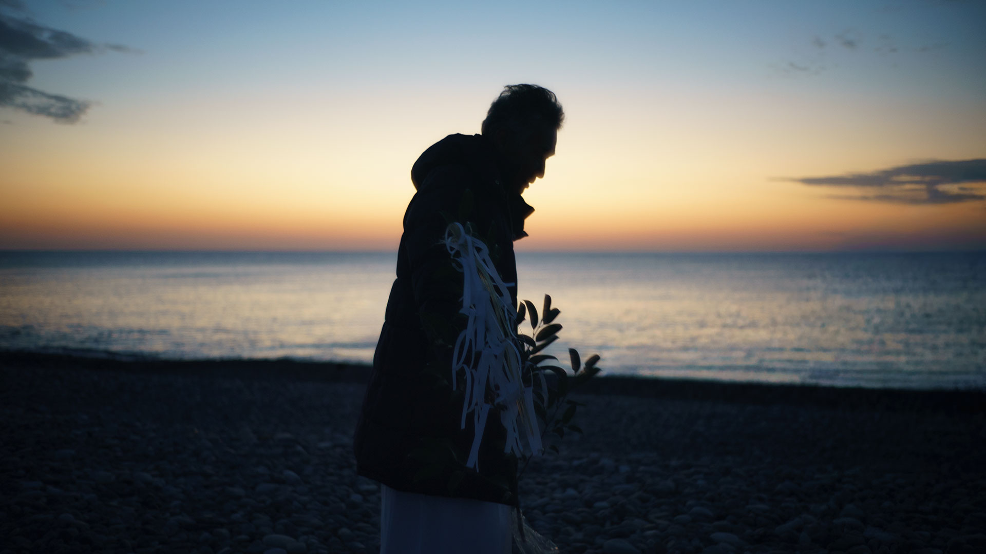 王子ヶ浜の波打ち際で、榊を手に静かに神事の準備を整える斎主。水平線には2026年の暖かい朝日の兆しが見える。 ｜ Oujigahama, Shingu, Wakayama ｜ SONY α7 ｜ 2026