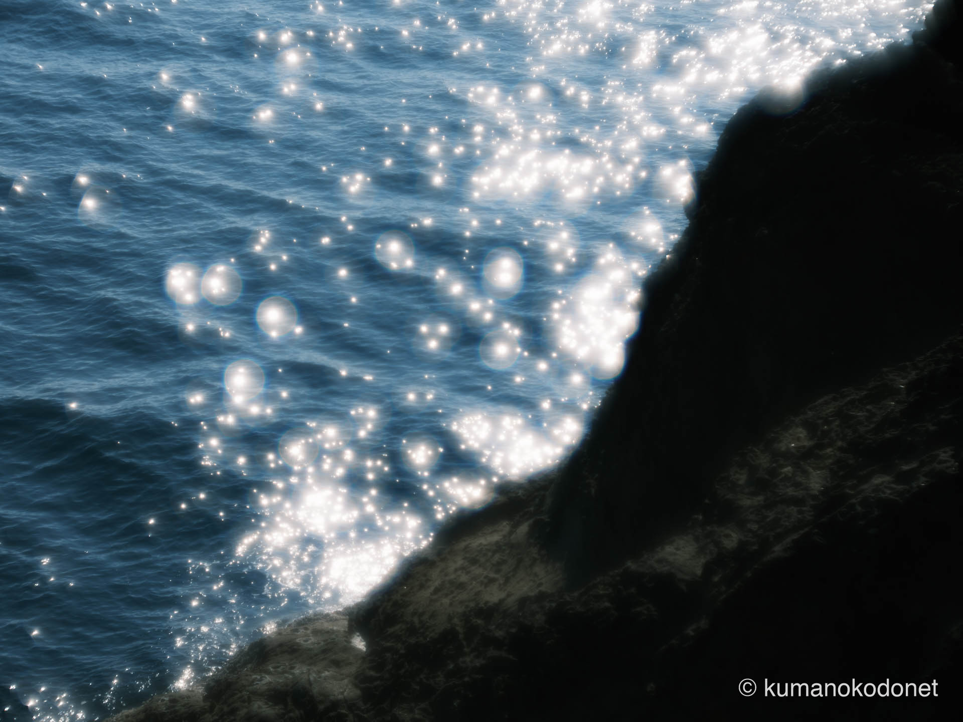 鬼ヶ城の崖の上から見下ろした、眩い陽光に照らされる海面の記録。音のない世界で彼女が見つめていた、煌めく光の粒と深い水の影が、美しくも切ない孤独感を際立たせている。