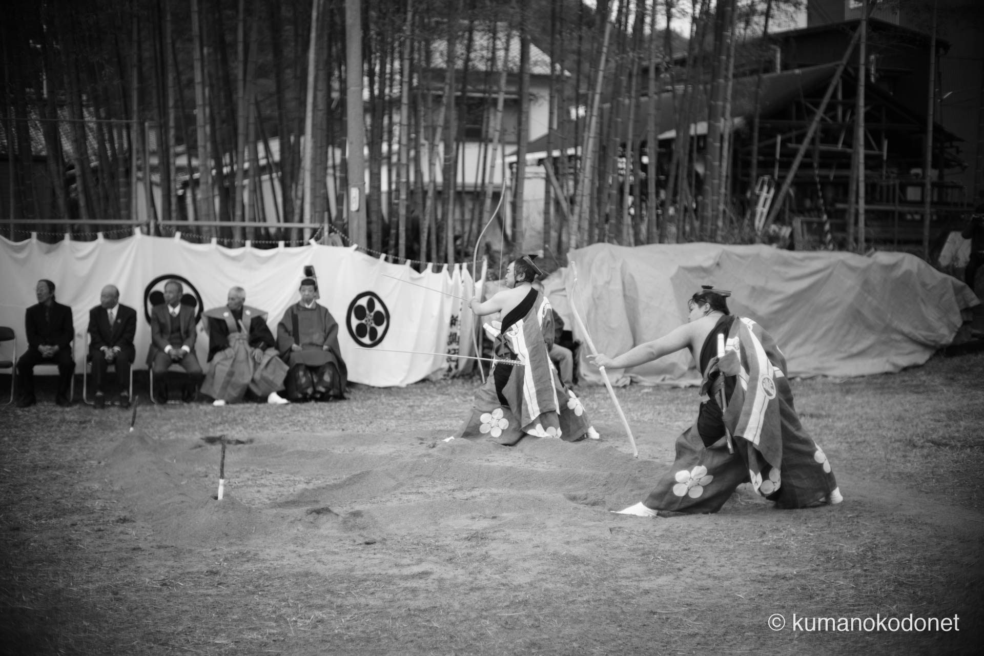 低い構えから弓を引き絞る射手