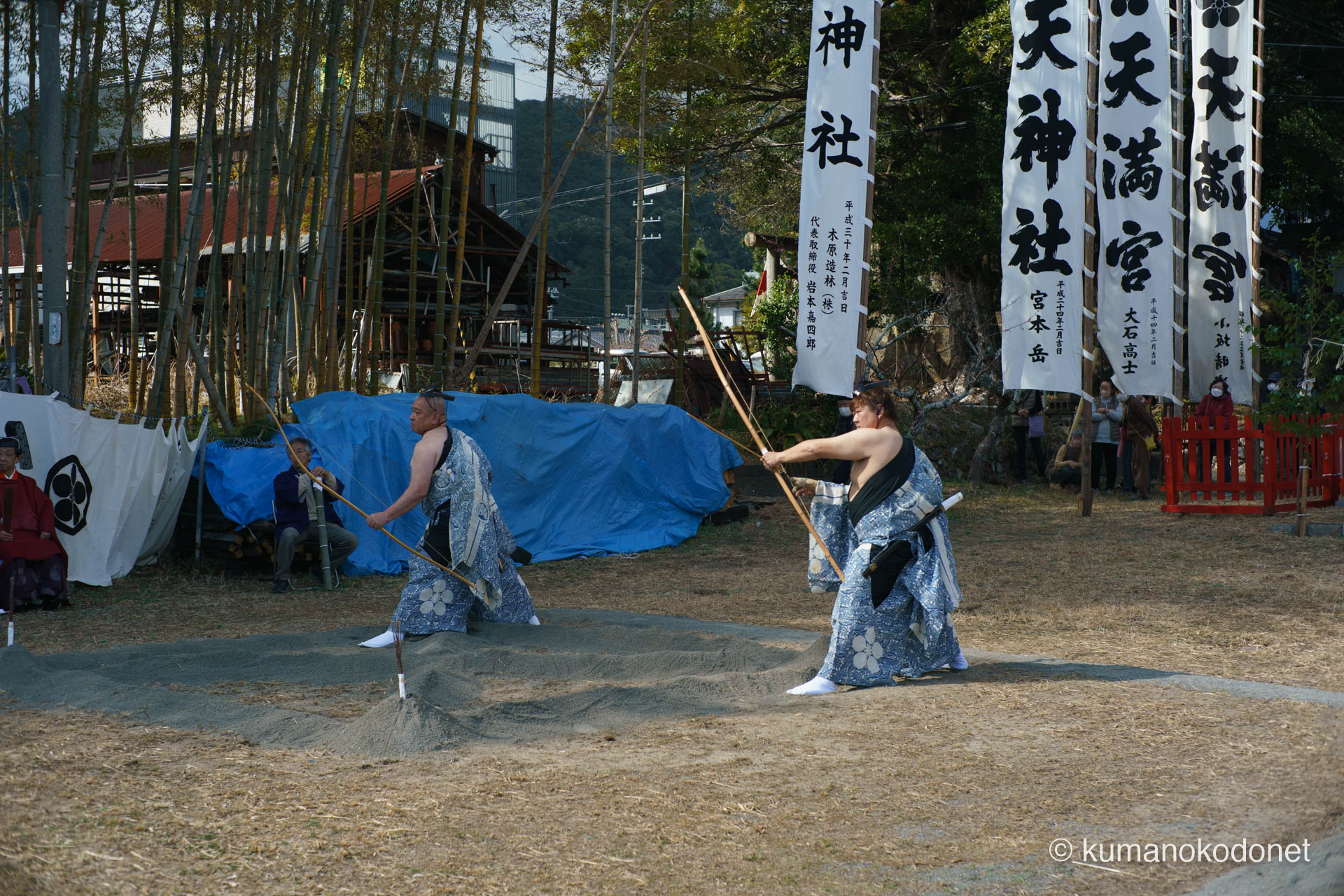 奉納幟の前で並び弓を構える二人の射手