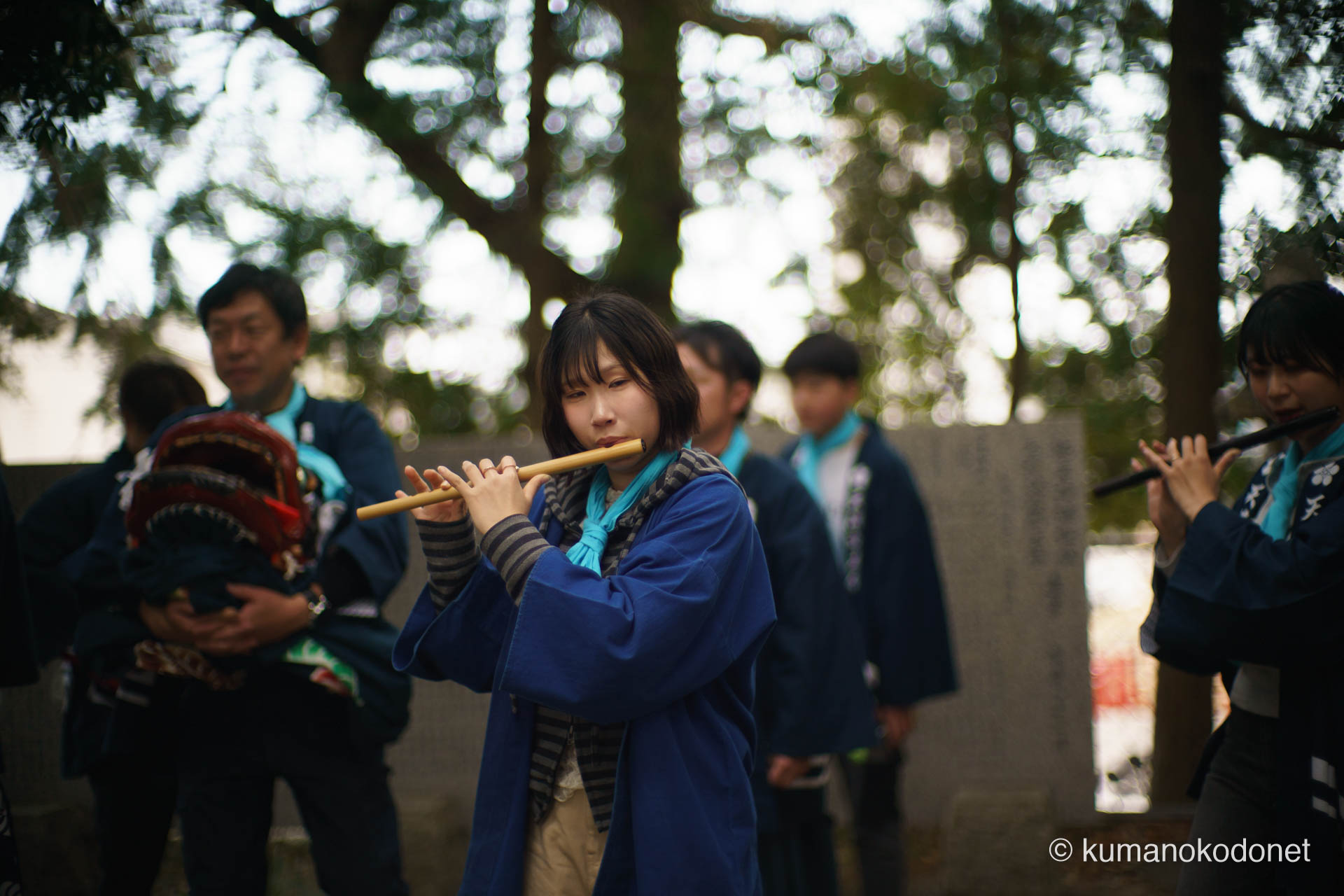 天満天神社の獅子舞奉納を彩る、澄んだ横笛の音色。青い法被を纏い、精神を集中させて笛を吹く女性たちの姿。背後では赤い獅子頭が待機し、音と舞が一体となって神前へ捧げられる瞬間の美しさを切り取った情景。 | Tenma Tenjinja, Nachikatsuura, Wakayama | SONY α7 | 2026