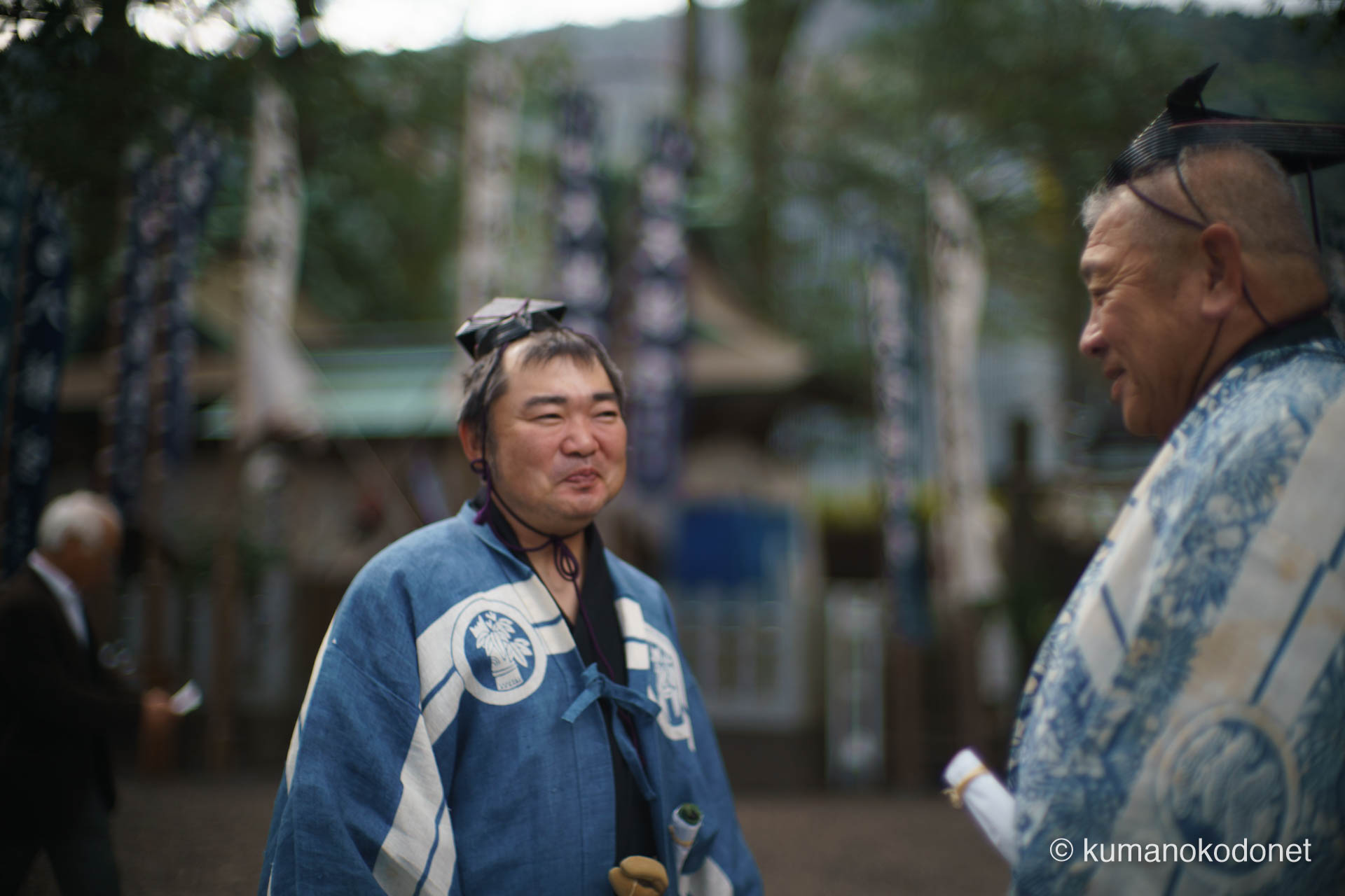 神事の合間、神酒を手に柔らかな表情を見せる射手たちの交流。これから始まる弓行事の緊張感を前に、仲間と語らい安堵の表情を浮かべる瞬間。地域の絆が、厳しい神事の中にも温かな空気を作り出している天満天神社の境内。| Tenma Tenjinja, Nachikatsuura, Wakayama | SONY α7 | 2026