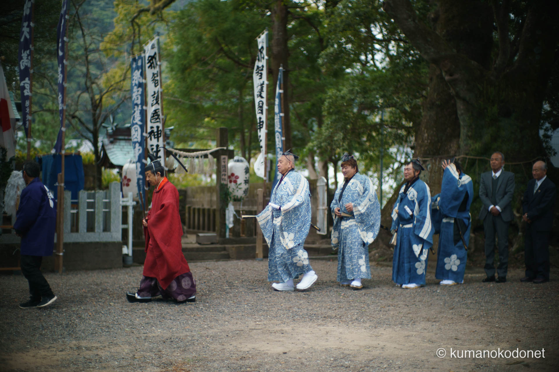 天満天神社の例大祭にて、高橋正樹宮司に導かれ、弓行事(ゆみぎょうじ)の舞台へと向かう四人の射手(射子)。伝統の青い装束を纏い、背筋を伸ばして歩む彼らの姿から、地域の安寧を願い直径約20cmの的を射抜く大役を前にした、厳かな緊張感が伝わる情景。 | Tenma Tenjinja, Nachikatsuura, Wakayama | SONY α7 | 2026