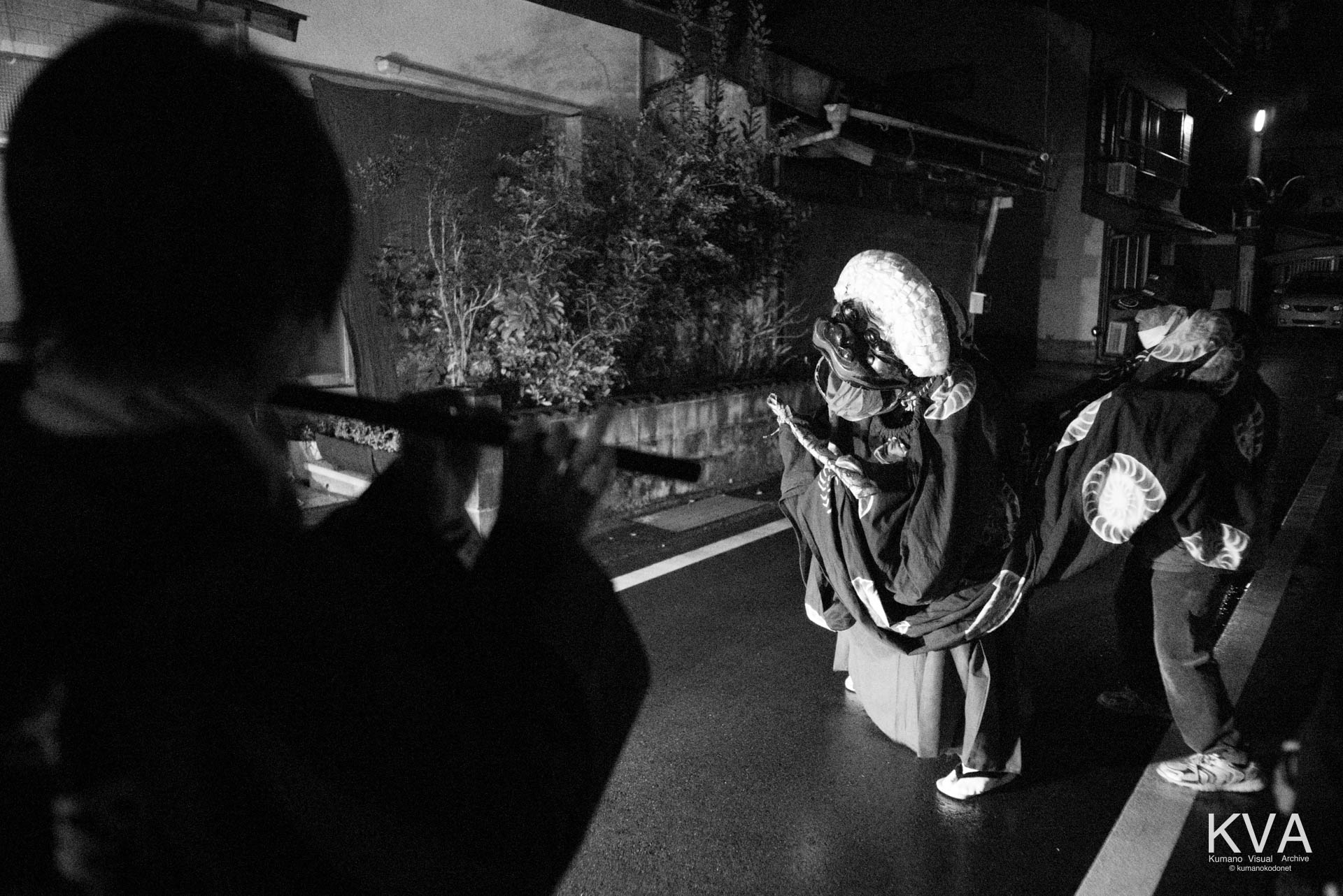 夜の路上で街灯に照らされて舞う地下回しの獅子舞