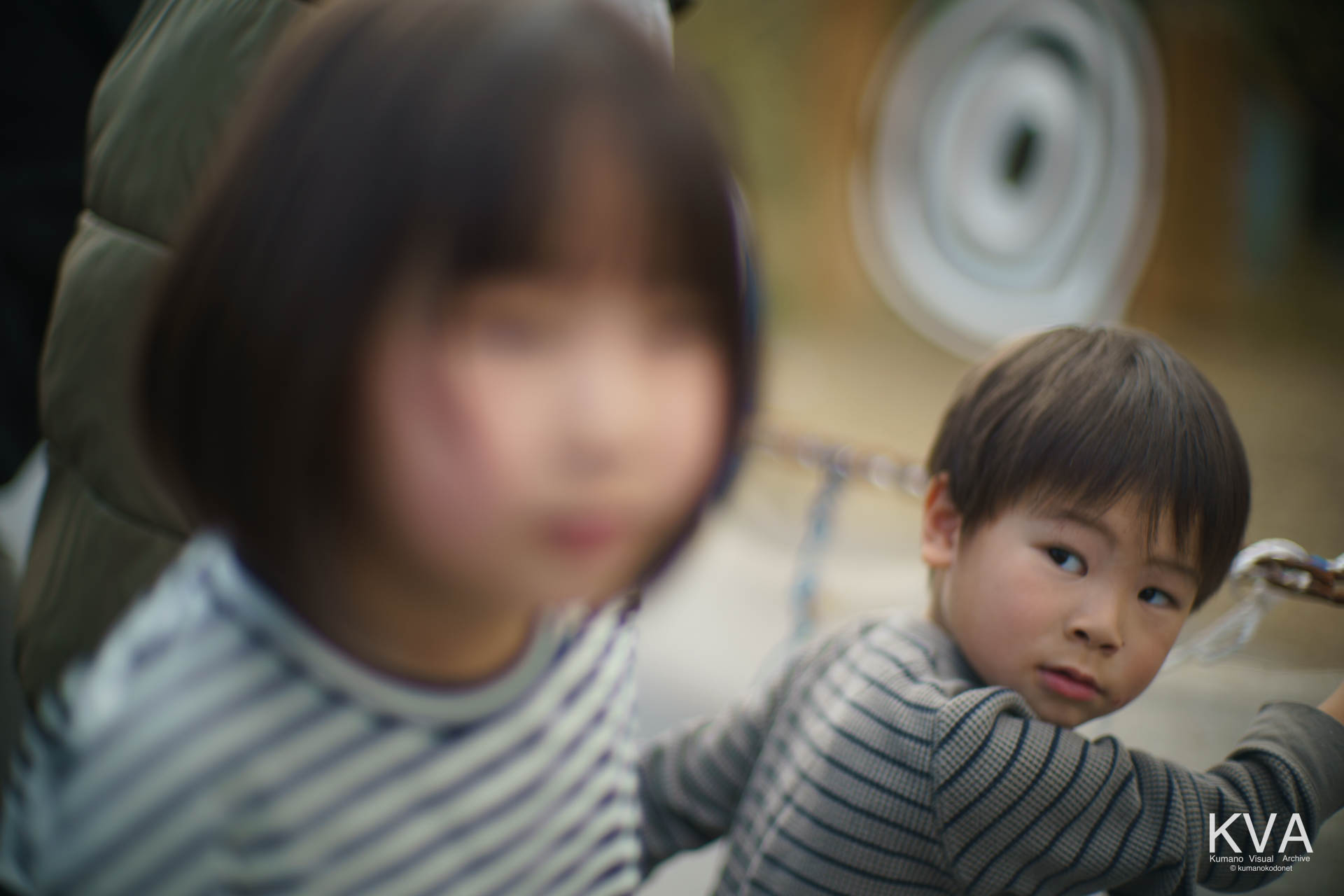 お揃いのボーダー柄の衣服を着た子供と背景の的の円紋