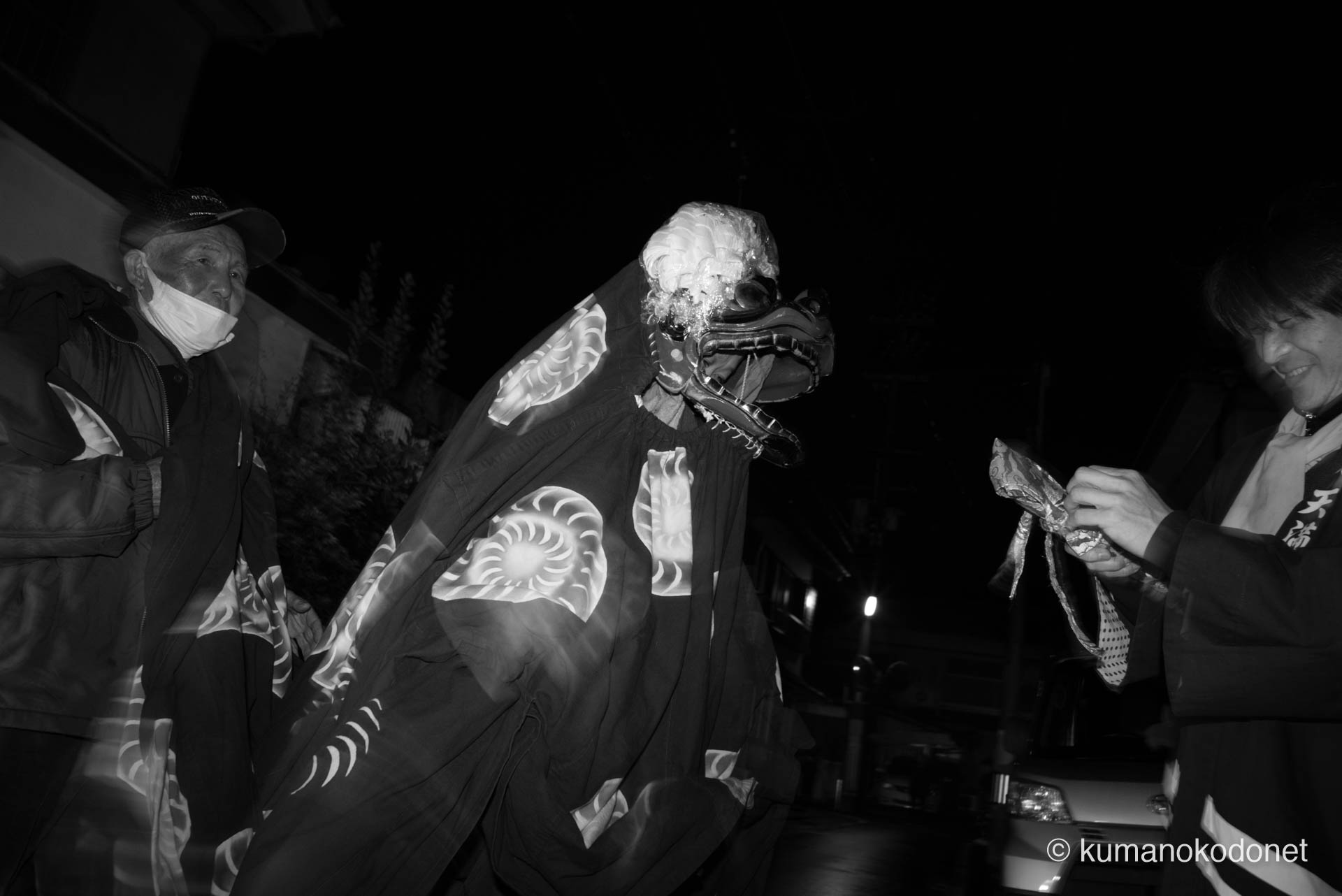 2024年の宵宮、地下まわしで玄関先を訪れた獅子舞と、それを見守る天満交友会のメンバー。獅子を操る者、奏でる者、そして支える仲間たちが一体となり、地域住民の無病息災を願う。天満天神社の例大祭を支える保存会の強い絆と、伝統継承の現場を捉えた温かな一幕。| Tenma Tenjinja, Nachikatsuura, Wakayama | SONY α7