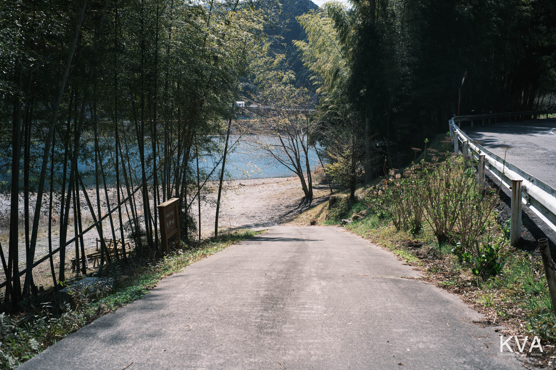 三重県紀宝町北桧杖。クマノザクラの咲く高台から、熊野川の広大な河原へと続く道。手前は舗装され、その先には三反帆が発着する砂利の河原が広がっている。三重県紀宝町北桧杖にて。 ｜ Path to Kumanogawa Riverbank ｜ GFX Classic Neg. ｜ 2026