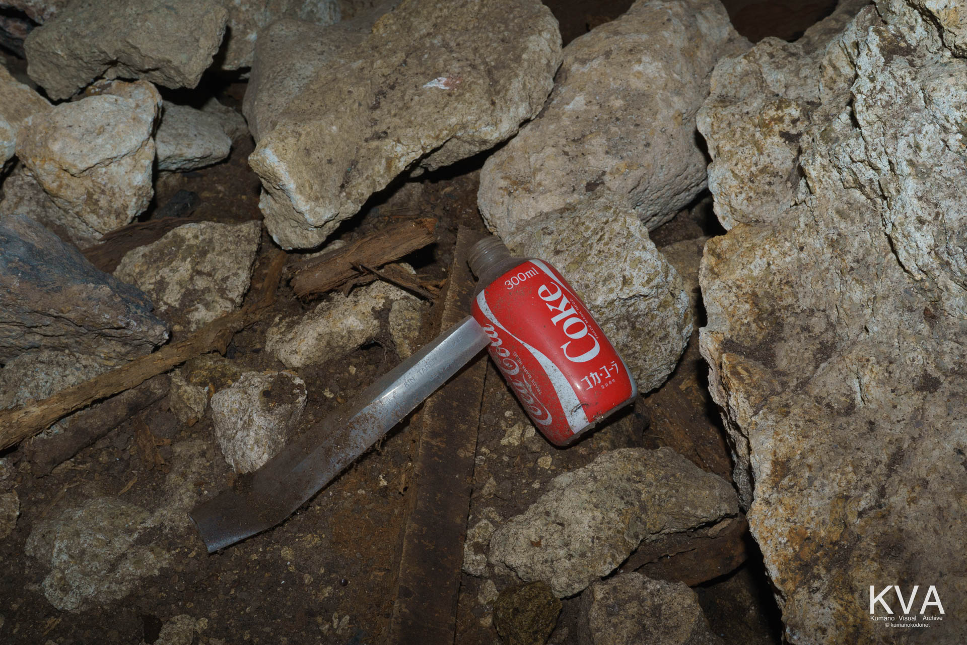 「籠る岩屋」に残された40年前の生活痕。参籠者が灯したであろうキャンドルの箱と、1980年代製コカ・コーラのボトル。現代の喧騒から隔離された時間のカプセル。 ｜ Kumano Deep South ｜ SONY α7 ｜ 2026