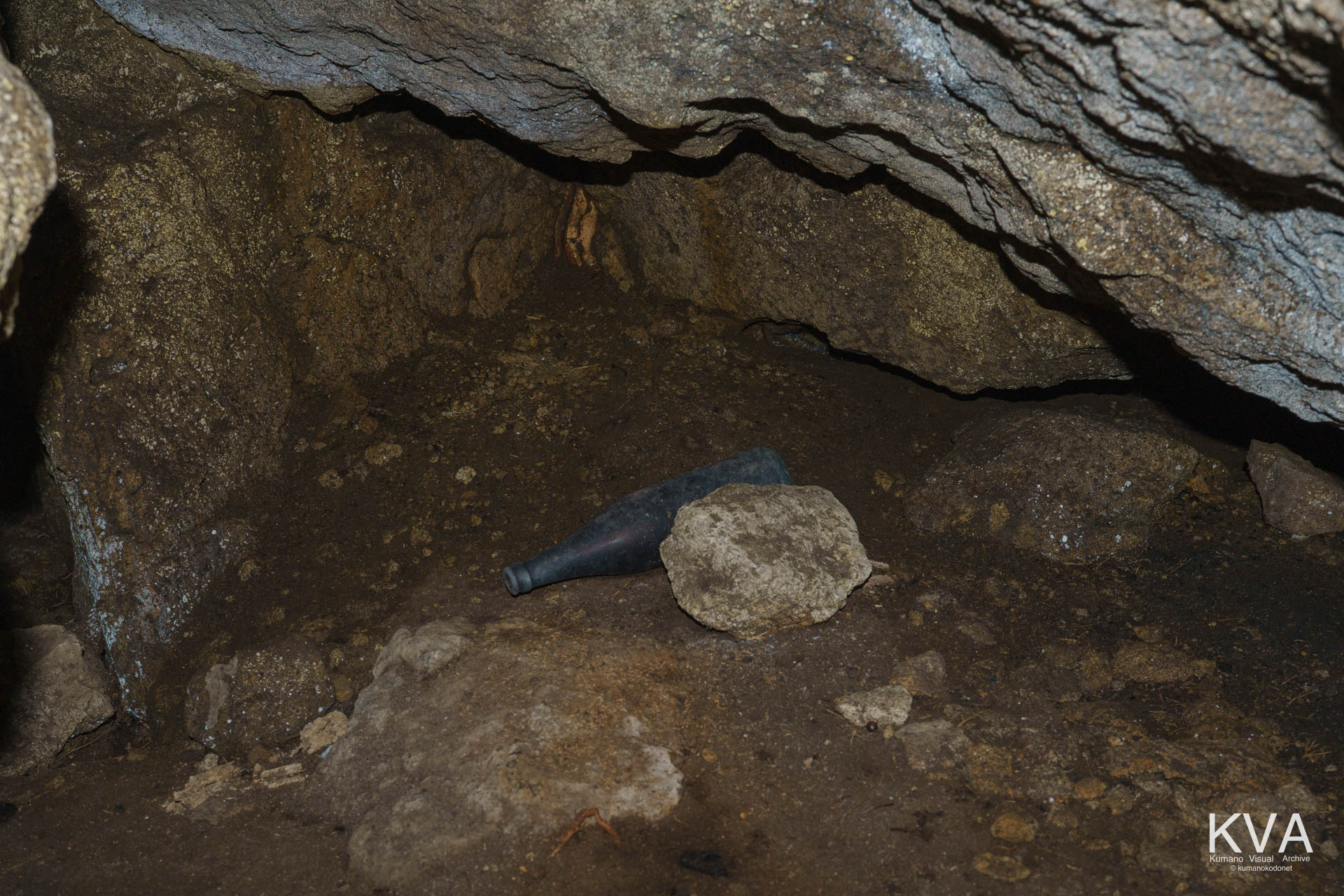 巌窟の奥まった場所に放置された古い酒瓶。単なる投棄物ではなく、神域への「献酒」として供えられたものが、40年の歳月を経てそのまま残された可能性が高い。 ｜ Kumano Deep South ｜ SONY α7 ｜ 2026
