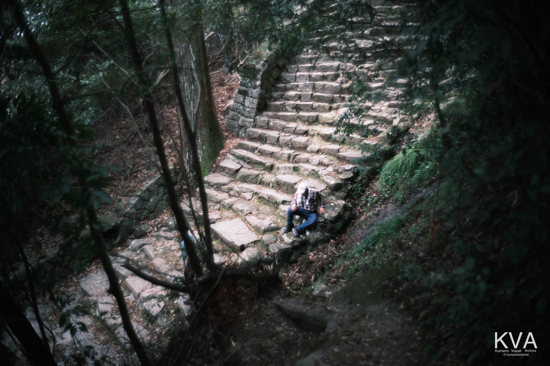 女坂の出口付近で腰を下ろして休息する高齢男性