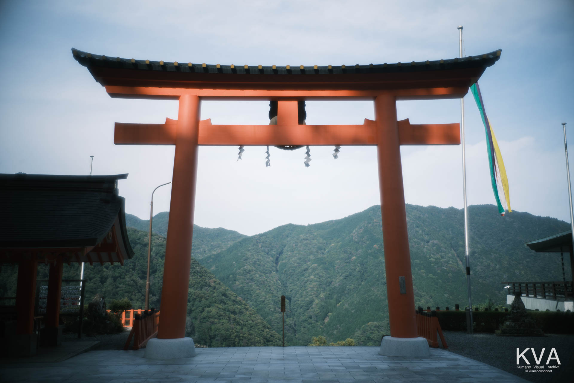 山並みを背景に立つ熊野那智大社の大鳥居全景、石畳の広場と五色の吹流し