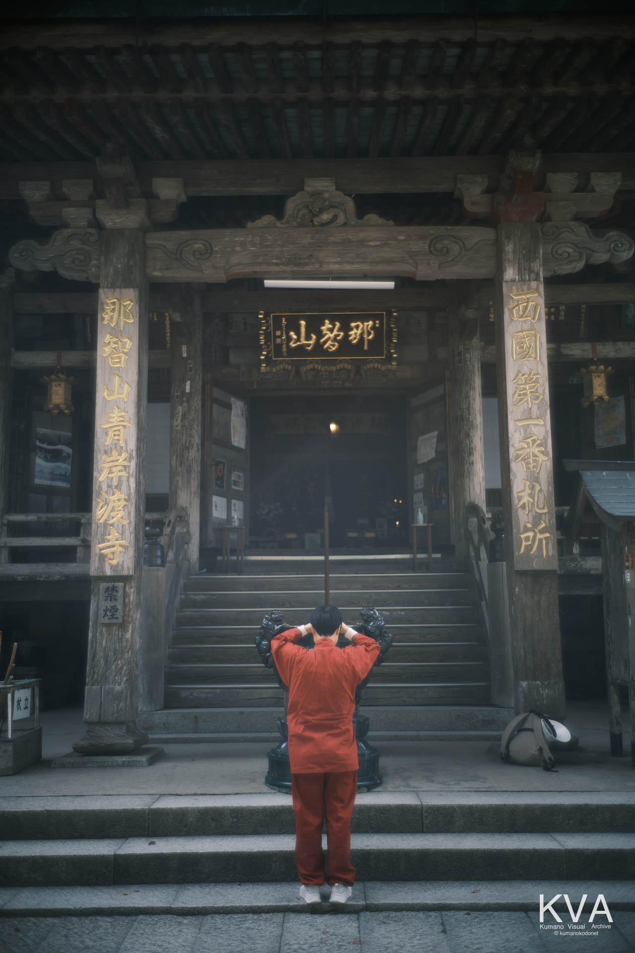 青岸渡寺本堂の向拝、香炉に線香を捧げ祈る外国人参拝者の後ろ姿