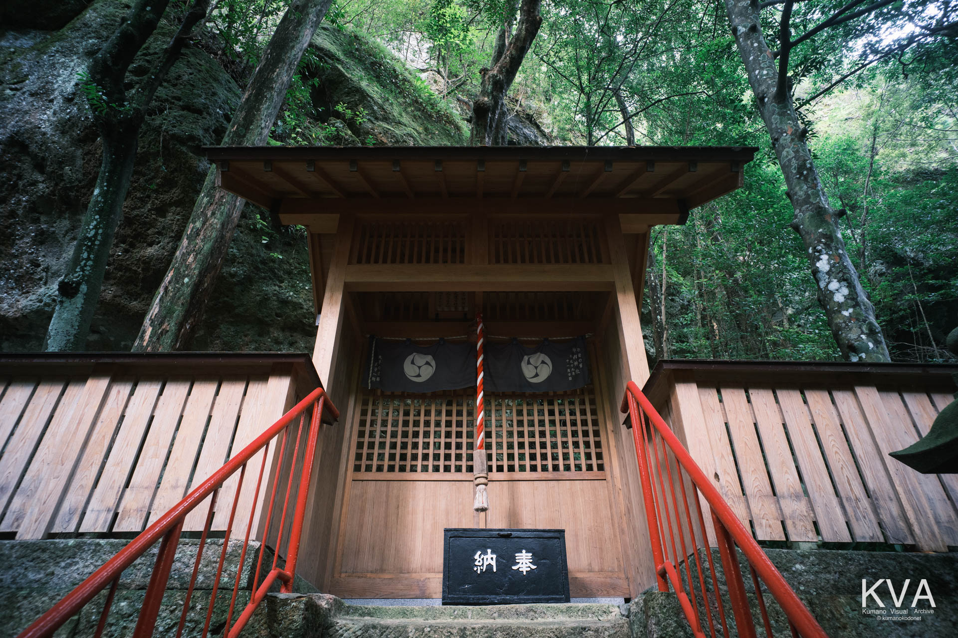 御神体の磐座を背にして建つ拝殿と朱色の手摺りがついた石