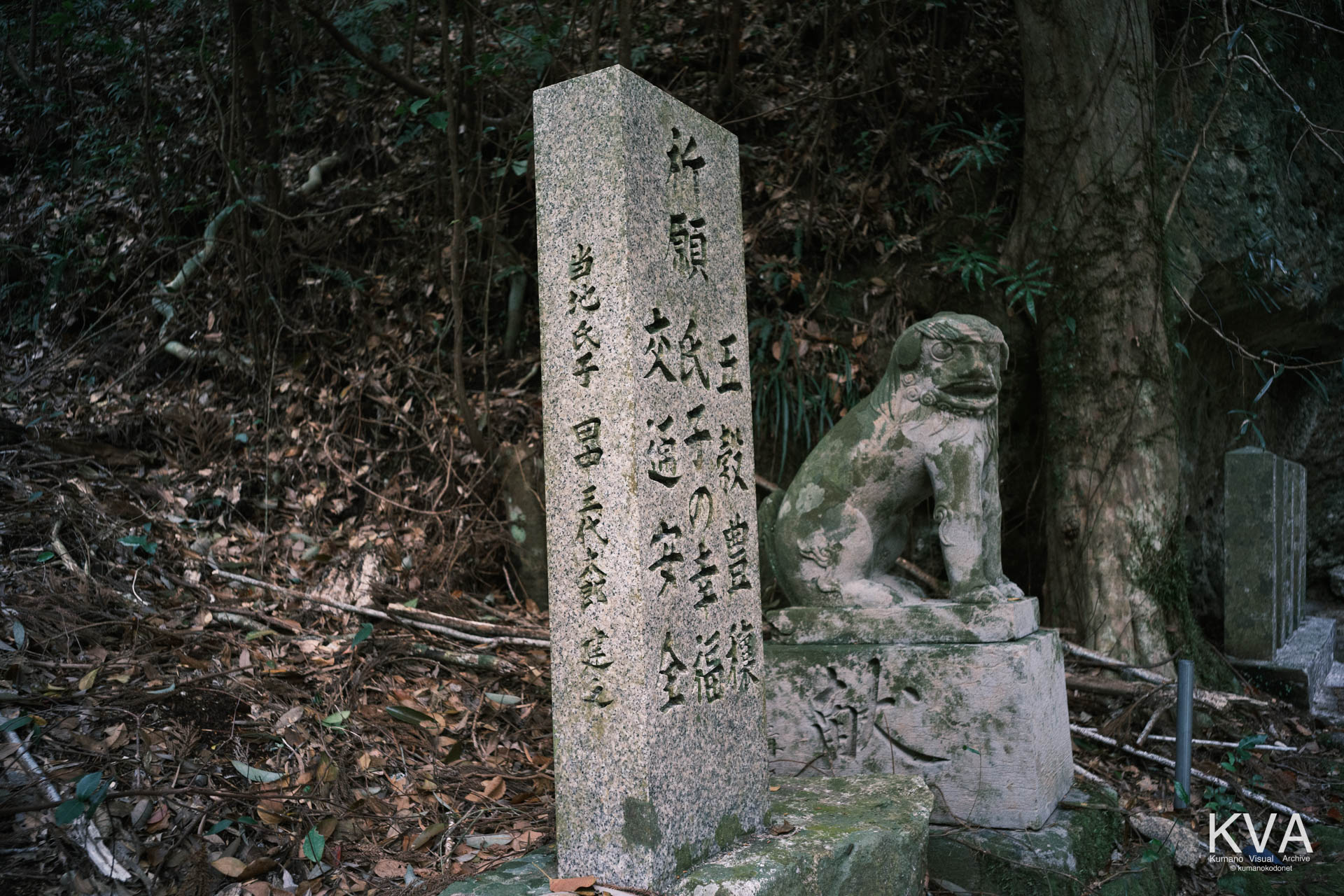 拝殿下に立つ祈願の石碑と奥に狛犬