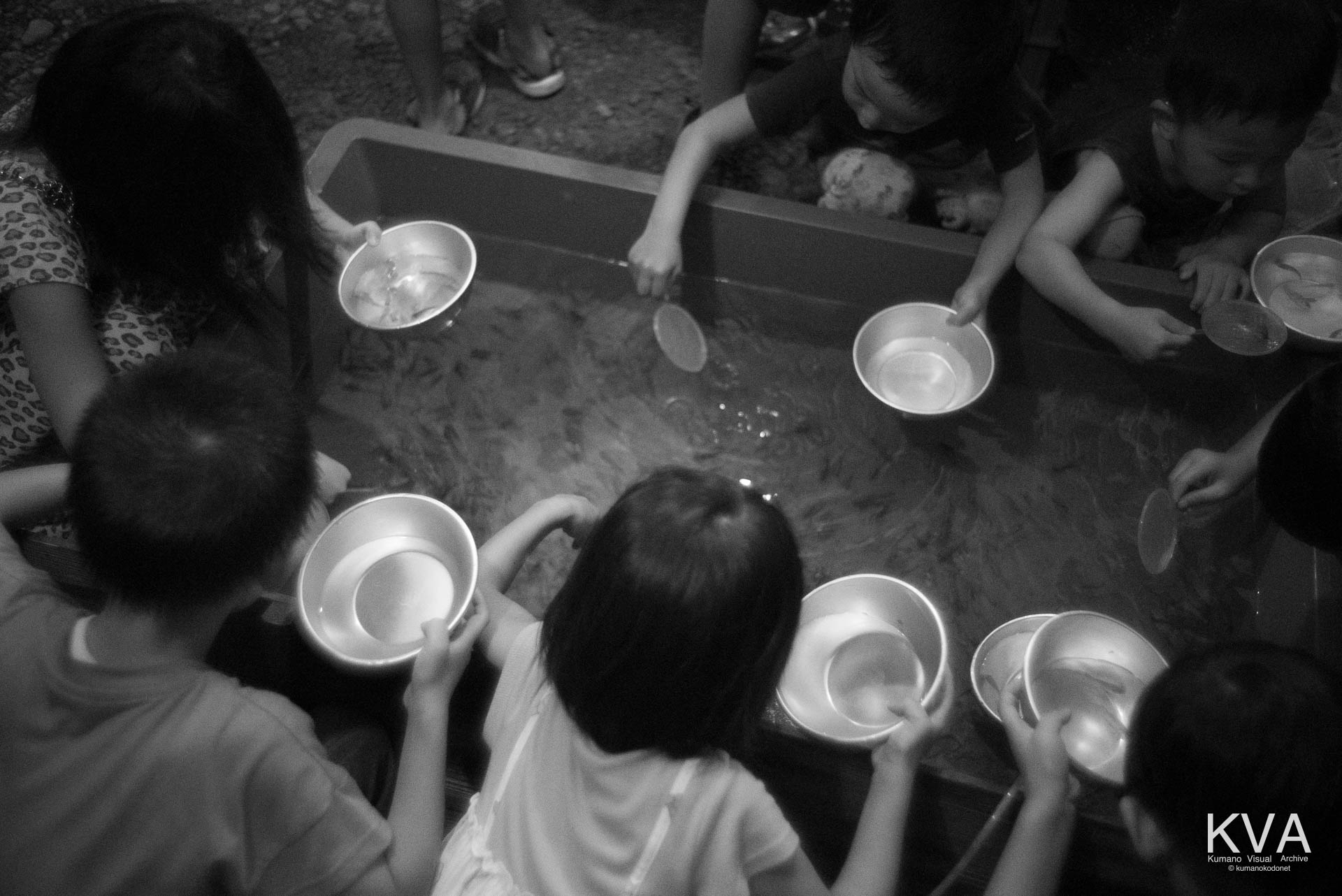 境内の屋台で金魚すくいを楽しむ子供たち