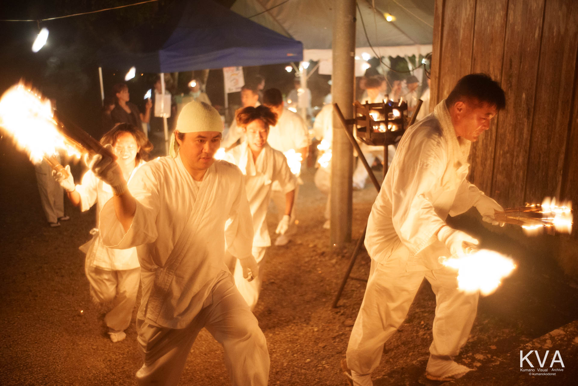 火のついた松明を手に裏山の目神八幡神社へ駆け上がる白装束の参加者たち