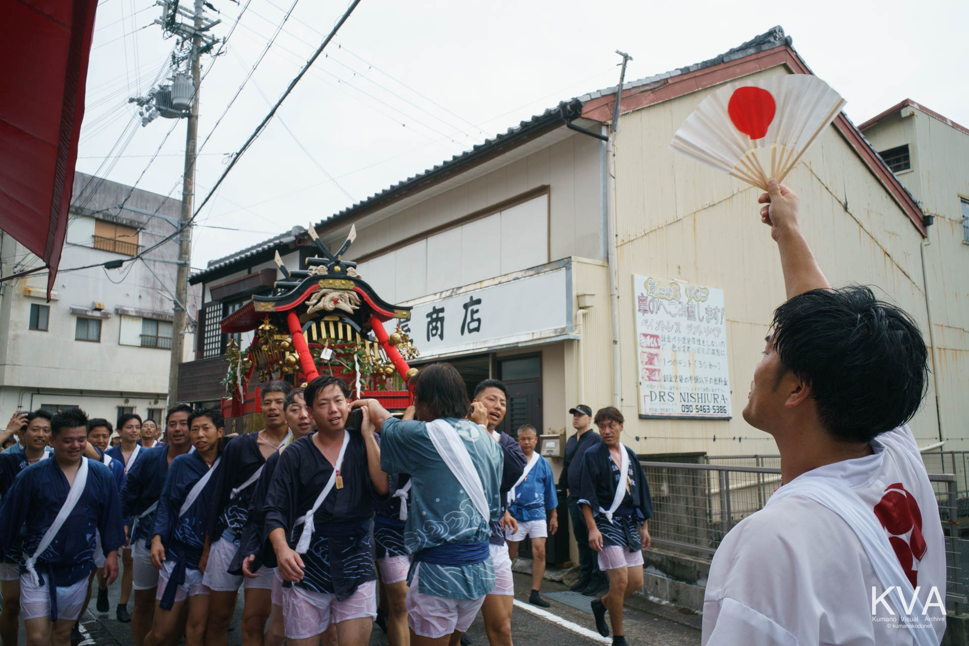 沿道の店舗前を進み町中を練り歩く神輿渡御の一行