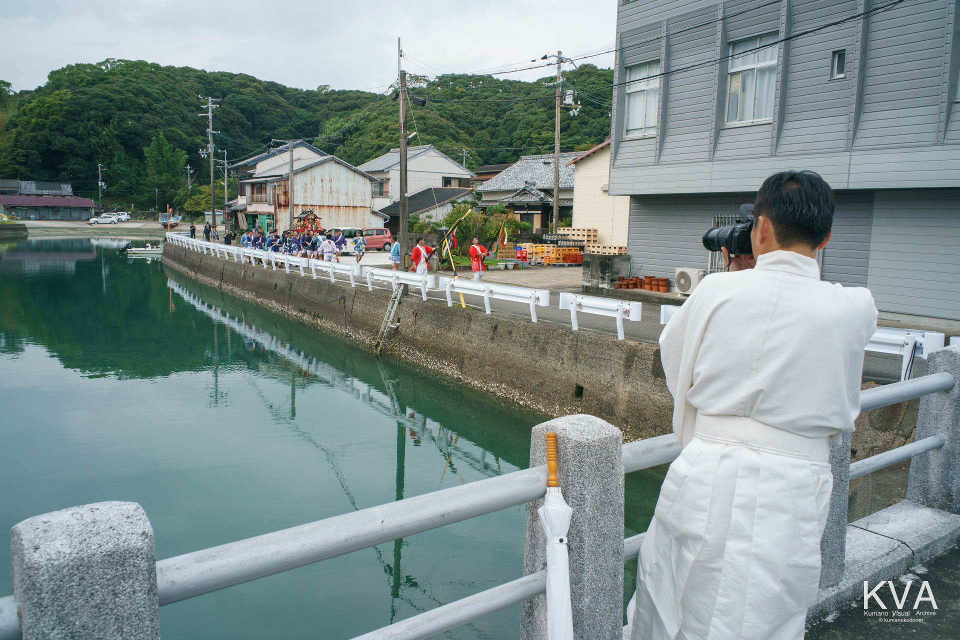 江南橋の欄干から神輿行列を撮影する神職