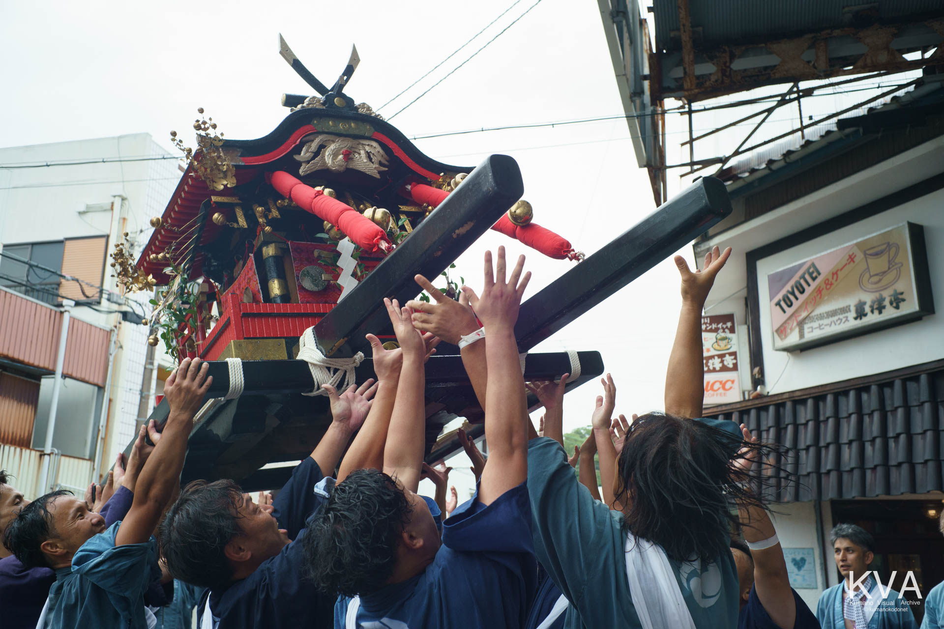 いざかた通り商店街で神輿を高く差し上げる担ぎ手たち
