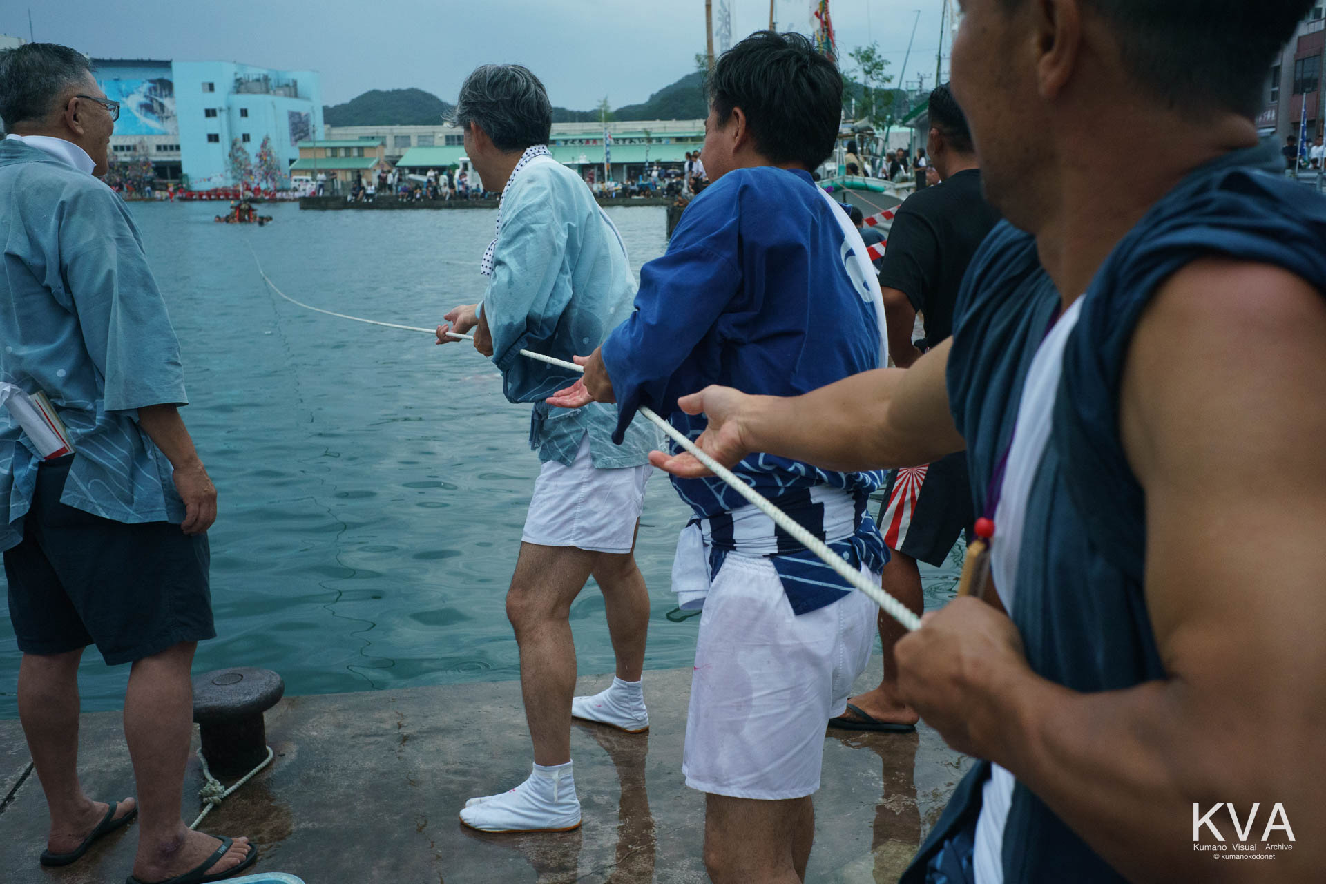 海上の櫂伝馬とロープを引き合う陸上の男たち