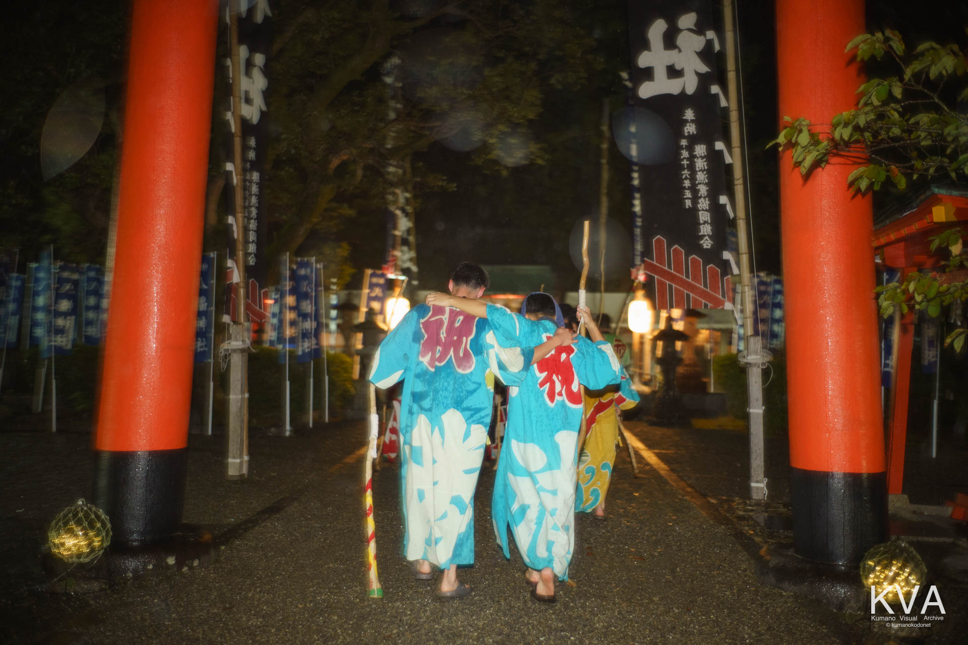 餅つき歌奉納へ向かい鳥居をくぐる愛友会の男たち