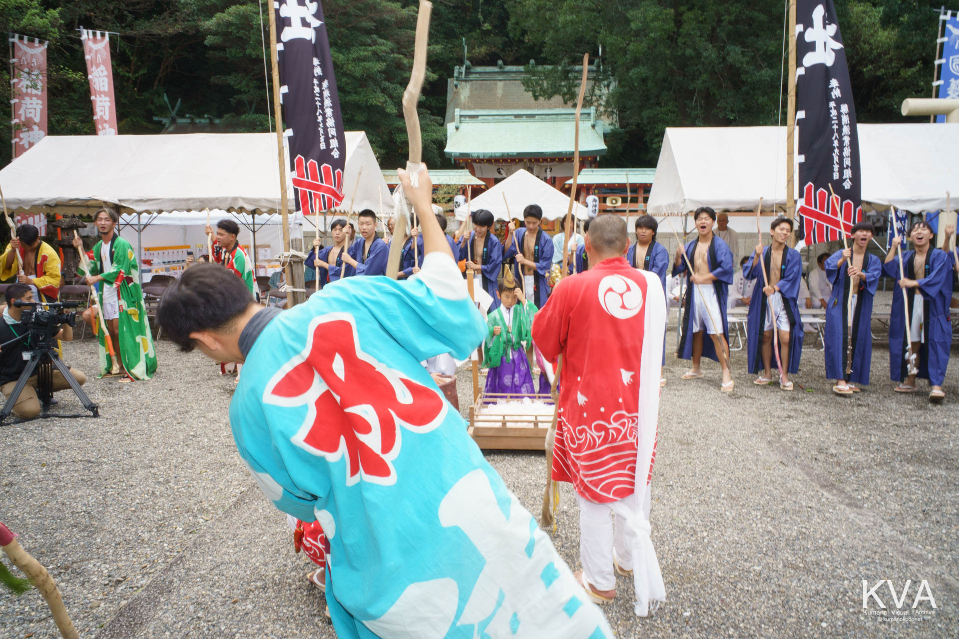 拝殿前で木棒を掲げて輪になり餅つき歌を奉納する餅つきたち